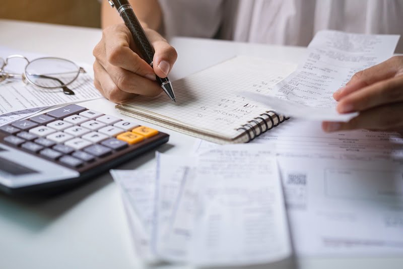 Stressed young woman checking bills, taxes, bank account balance and calculating expenses in the living room at home