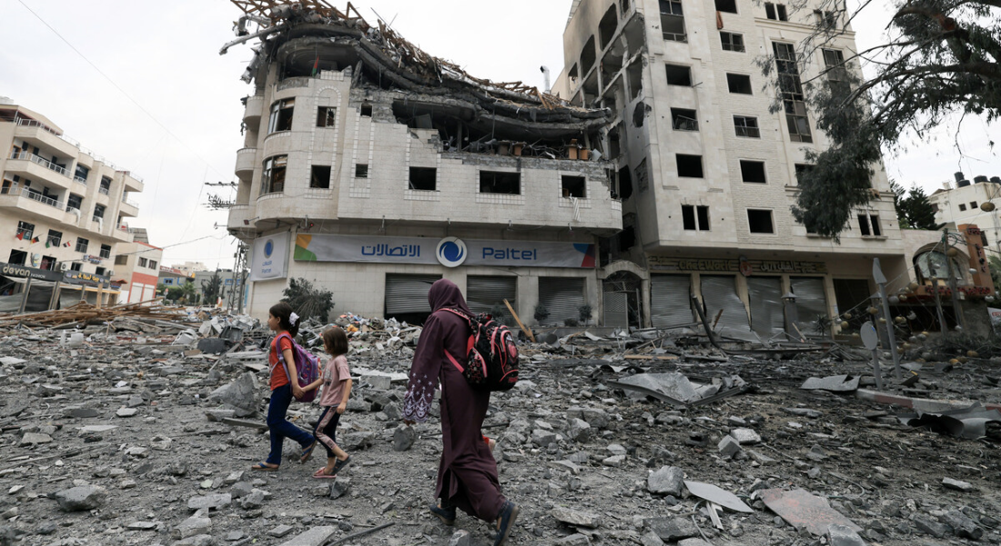Família palestina caminha diante de ruínas de prédios bombardeados na Faixa de Gaza - Foto: Mahmud Hams/AF