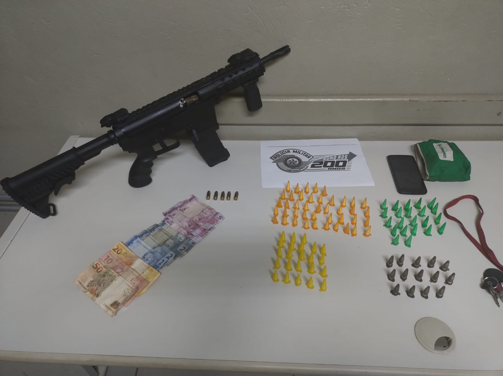 O armamento de uso restrito estava com um homem. Com ele, foram apreendidas também várias porções de drogas