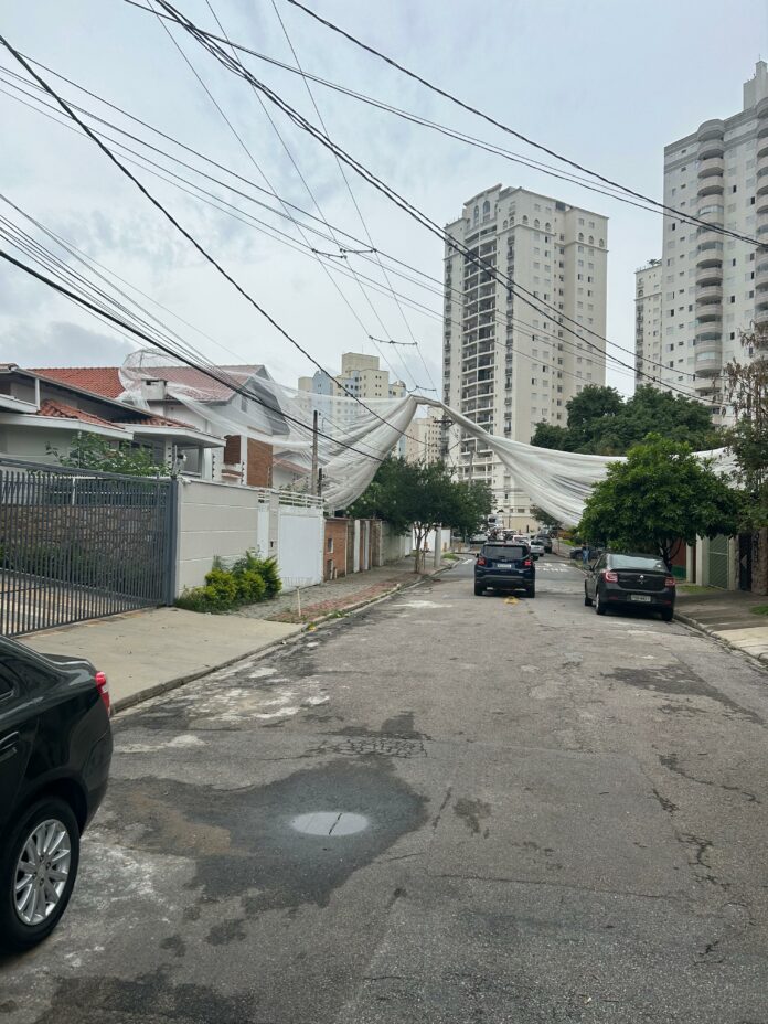 Com a ventania, tela de proteção de obra cai de prédio e atinge fiação elétrica de rua em São José