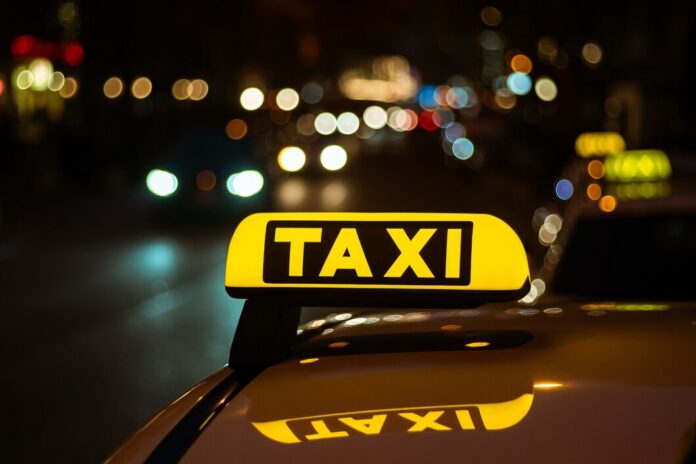 placa-amarela-e-preta-de-taxi-colocada-em-cima-de-um-carro-a-noite_181624-10624