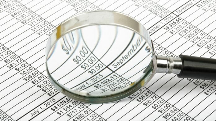 Tabela de valores com uma lupa em destaque sobre dados financeiros, representando análise de contribuições para aposentadoria por pontos.